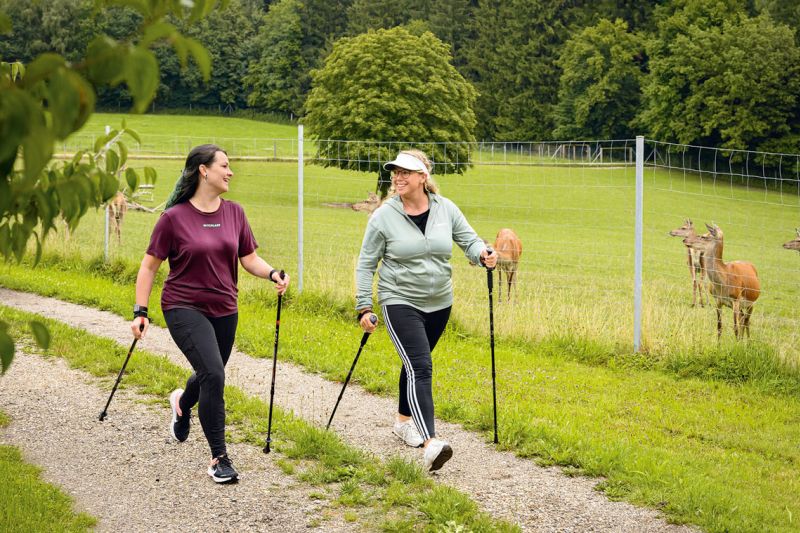 Zwei Frauen beim Nordic Walking am Hirschgehege des Giglerhofs bei Bad Birnbach, dahinter Hirsche auf der Weide