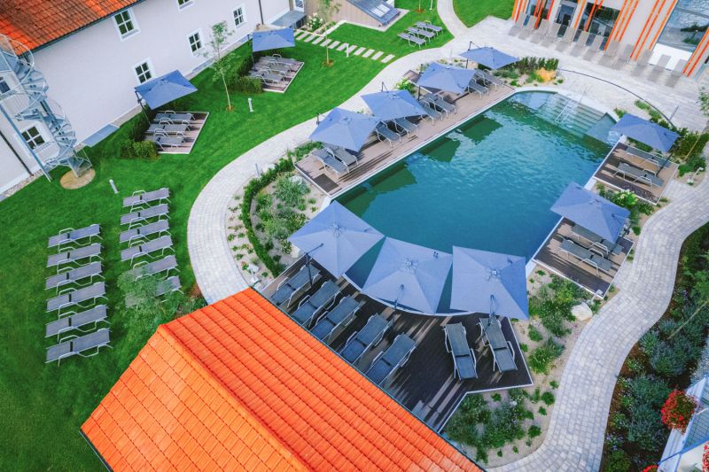 Luftaufnahme des Außenpools mit Sonnenschirmen, Liegen und Garten des Hotels Churfürstenhof
