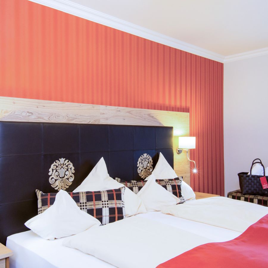 Schlafzimmer der Suite Royal im Hotel Churfürstenhof Bad Birnbach mit Doppelbett vor roter Akzentwand