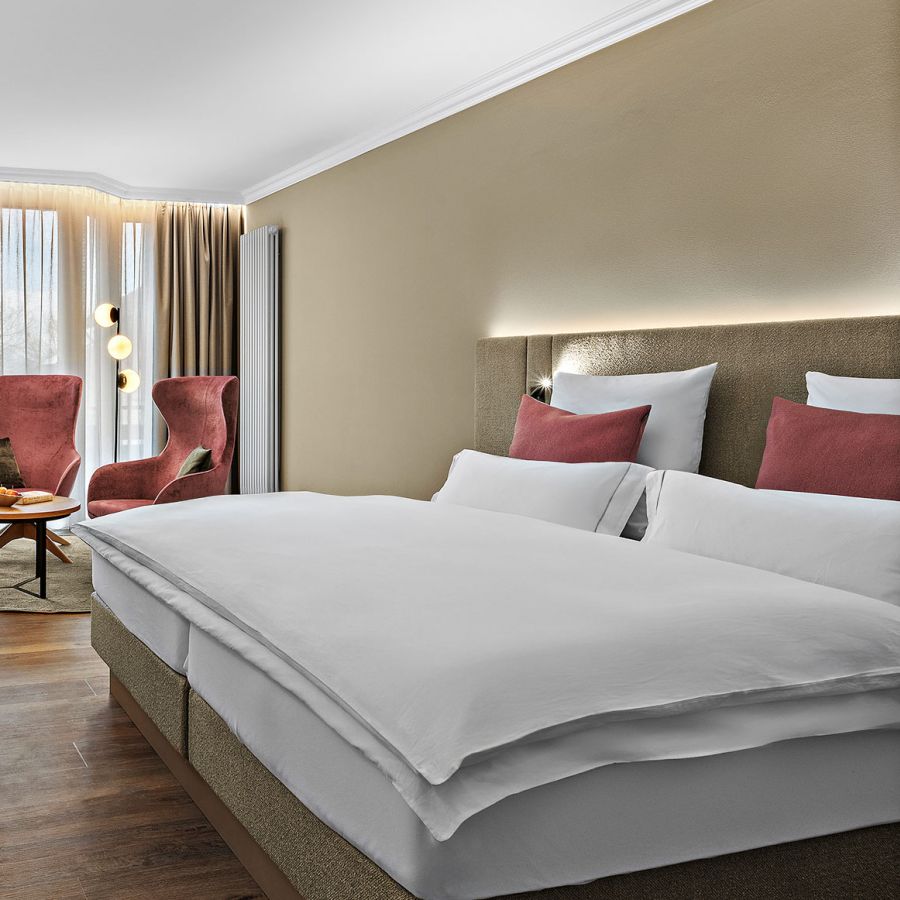 Zimmer Komtess im Wellnesshotel Churfürstenhof: Doppelbett, rote Sessel und Schreibtisch in warmen Farben