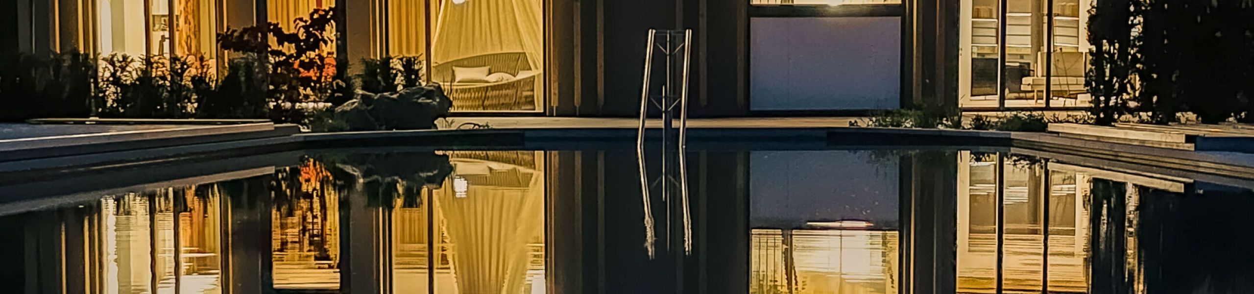 Beleuchtete Fassade des Hotel Churfürstenhof spiegelt sich abends im Außenpool