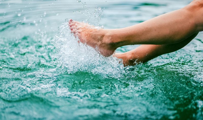 Füße planschen erfrischend im grünblauen Wasser