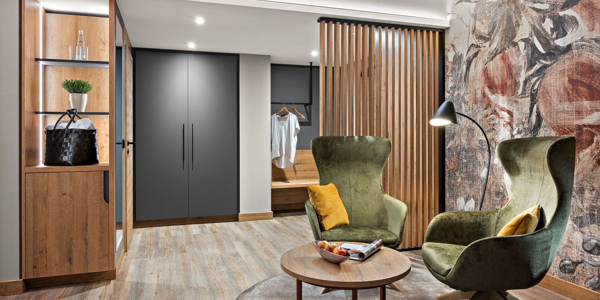 Zimmer Prinzess im Hotel Churfürstenhof Bad Birnbach mit grünen Sesseln, Holzlamellen und Garderobe