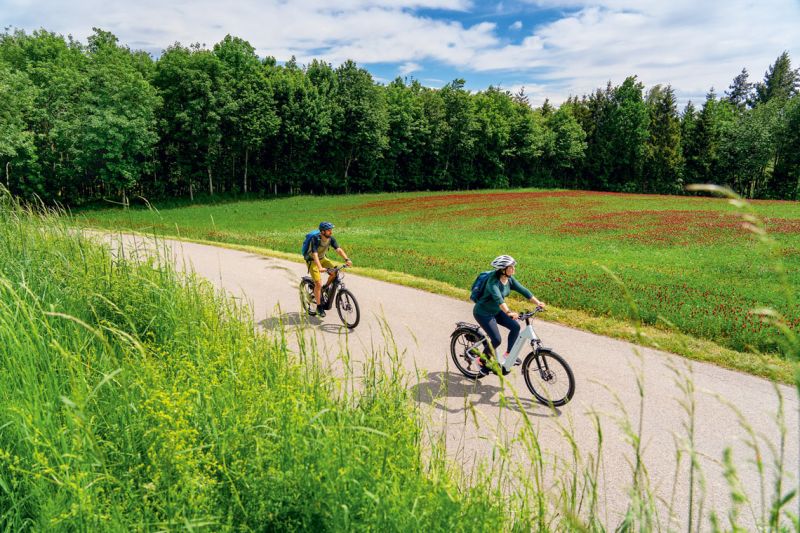 Zwei Radfahrer auf E-Bikes unterwegs auf der Bruder-Konrad-Tour durch die grüne Rottaler Landschaft