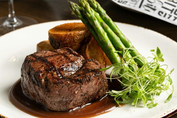 Grilled beef fillet with green asparagus, potatoes and gravy, served with chips and salad