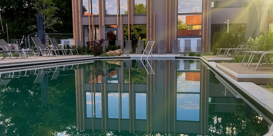 Außenpool des Hotels Churfürstenhof am Abend, das Badehaus spiegelt sich im Wasser