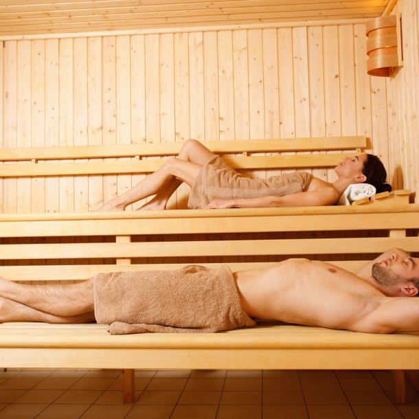 Mann und Frau entspannen mit Handtüchern auf den Holzbänken einer Sauna im Wellnesshotel Churfürstenhof