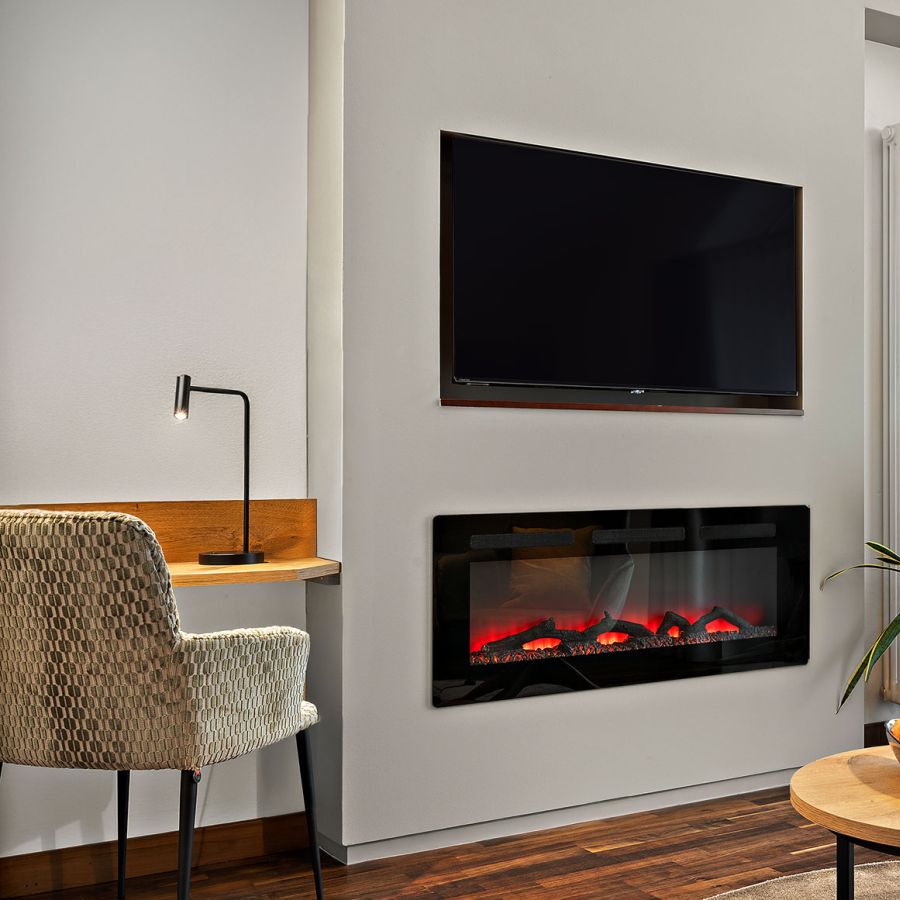 Wohnbereich der Komfort-Suite im Wellnesshotel Churfürstenhof mit Elektrokamin, TV, Sessel und Stehlampe