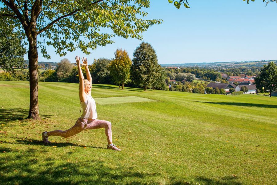 Frau bei einer Yoga-Übung unter einem Baum am Rottaler Baum-Yoga-Weg mit Blick über Bad Birnbach