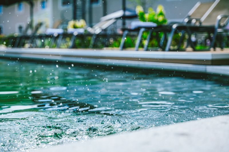Wasserspritzer am Beckenrand des Außenpools, dahinter Sonnenliegen am Hotel Churfürstenhof