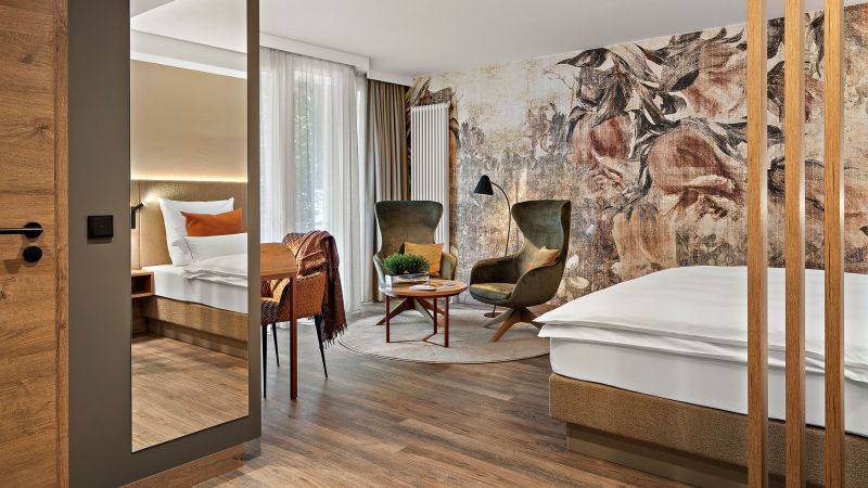 Zimmer Prinzess im Wellnesshotel Churfürstenhof mit floraler Wandgestaltung, grünen Sesseln und großem Spiegel