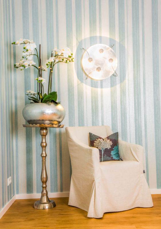 Heller Sessel mit gemusterten Kissen neben Orchideen-Dekoration im Hotel Churfürstenhof