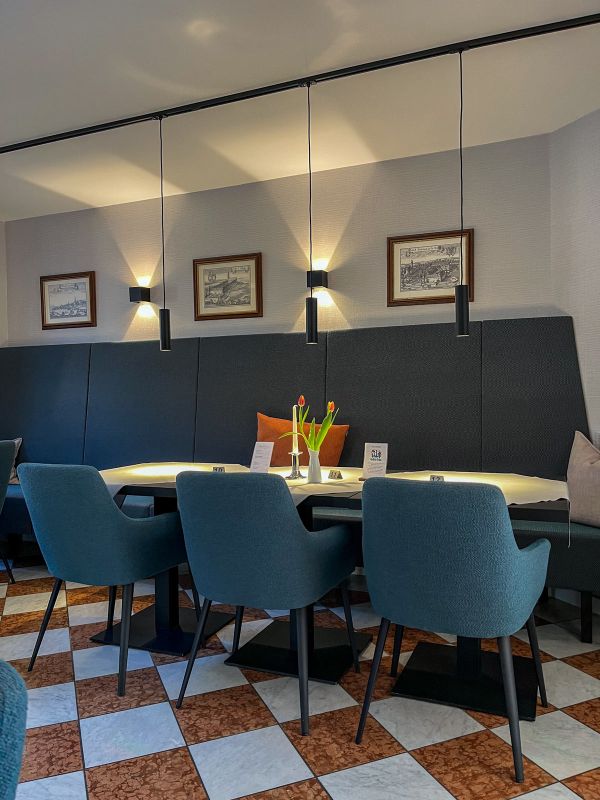 Restaurant im Hotel Churfürstenhof mit blauen Polsterstühlen, Schachbrettboden und Tulpen auf dem Tisch