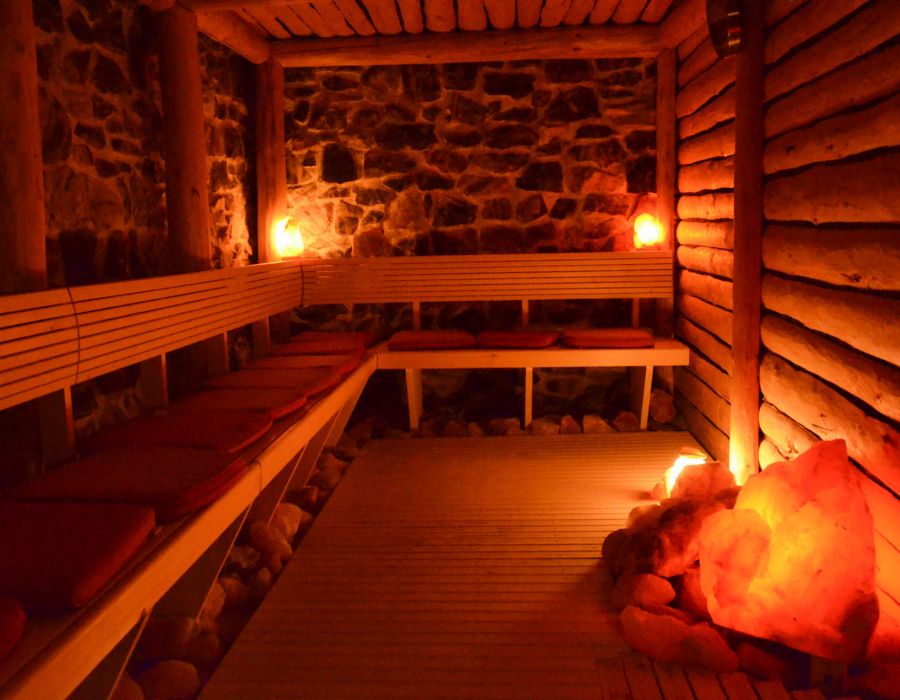Stimmungsvoll beleuchtete Sauna mit Natursteinwand und leuchtenden Salzkristallen im Hotel Churfürstenhof