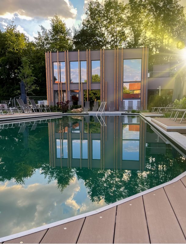 Außenpool des Hotels Churfürstenhof am Abend, das Badehaus spiegelt sich im Wasser