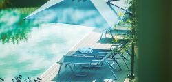 Sonnenliegen mit gerollten Handtüchern unter einem Sonnenschirm am Außenpool des Hotels Churfürstenhof