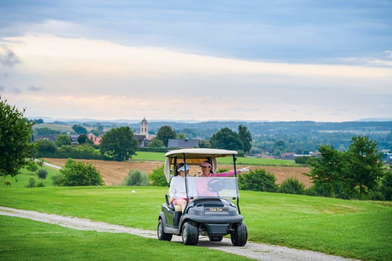 Zwei Golferinnen im Golfcart im Bella Vista Golfpark mit Blick über das hügelige Rottal